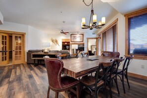Un coin repas avec une table et des chaises en bois, un lustre et une cheminée.