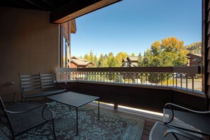 Ein Balkon mit Metallgeländer, zwei Metallstühle, einem kleinen Tisch und einem gemusterten Teppich.
