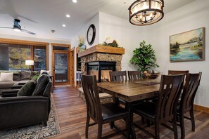 A dining area with a wooden table and chairs, a stone fireplace, and a painting on the wall. - AL4203 | Beautiful and Professionally Decorated | 10 Hot Tubs | Air Chilling (Steamboat Springs)