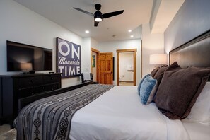 A bedroom with a large bed, a TV, a ceiling fan, and a sign that reads "ON Mountain TIME". - AL4203 | Beautiful and Professionally Decorated | 10 Hot Tubs | Air Chilling (Steamboat Springs)