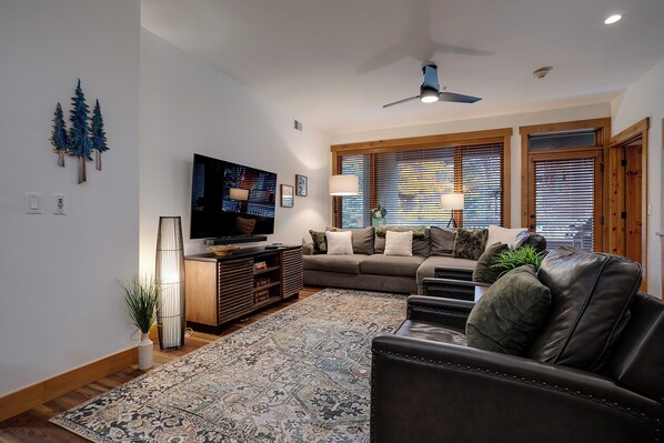 A living room with a flat-screen TV, a sofa, a coffee table, and a patterned rug. - AL4203 | Beautiful and Professionally Decorated | 10 Hot Tubs | Air Chilling (Steamboat Springs)