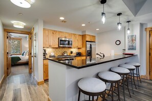 A modern kitchen with wooden cabinets, stainless steel appliances, and a central island with bar stools. - AL4205 | Home Away from Home | Modern Décor | Air Chilling | Close to Slopes (Steamboat Springs)