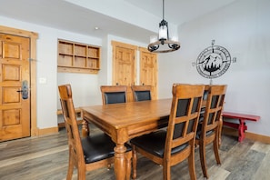 A dining area with a wooden table and chairs, a wall-mounted compass decoration, and wooden cabinets. - AL4205 | Home Away from Home | Modern Décor | Air Chilling | Close to Slopes (Steamboat Springs)
