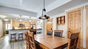 Una cocina amplia con armarios de madera, una isla central y un comedor con mesa y sillas de madera.