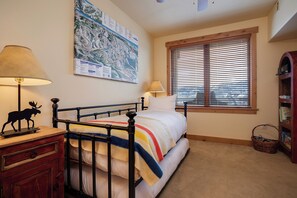 A bedroom with a bed, a map on the wall, a window with blinds, a lamp, and a bookshelf. - AL4206 | Gorgeous Mountain Retreat | Close to Mountain | Pools | Air Chilling (Steamboat Springs)