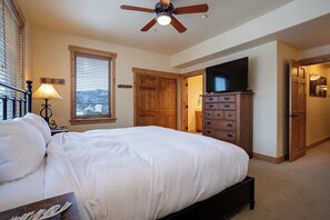 A bedroom with a bed, a ceiling fan, a TV, wooden cabinets, and a window with blinds. - AL4206 | Gorgeous Mountain Retreat | Close to Mountain | Pools | Air Chilling (Steamboat Springs)