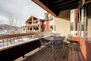 Eine Holzterrasse mit rundem Tisch und Stühlen, mit Blick auf ein Wohngebiet mit mehreren Gebäuden.