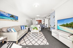 Ein modernes Wohnzimmer mit Sofa, Couchtisch und Flachbildfernseher.