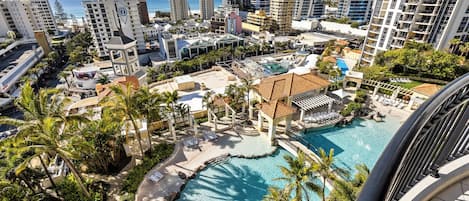 A resort with a large pool, palm trees, and high-rise buildings in the background.