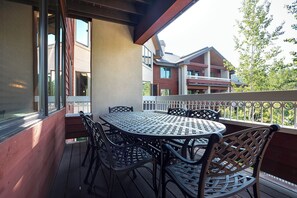 Een balkon met een metalen tafel en stoelen, met uitzicht op een gebouw met meerdere balkons.