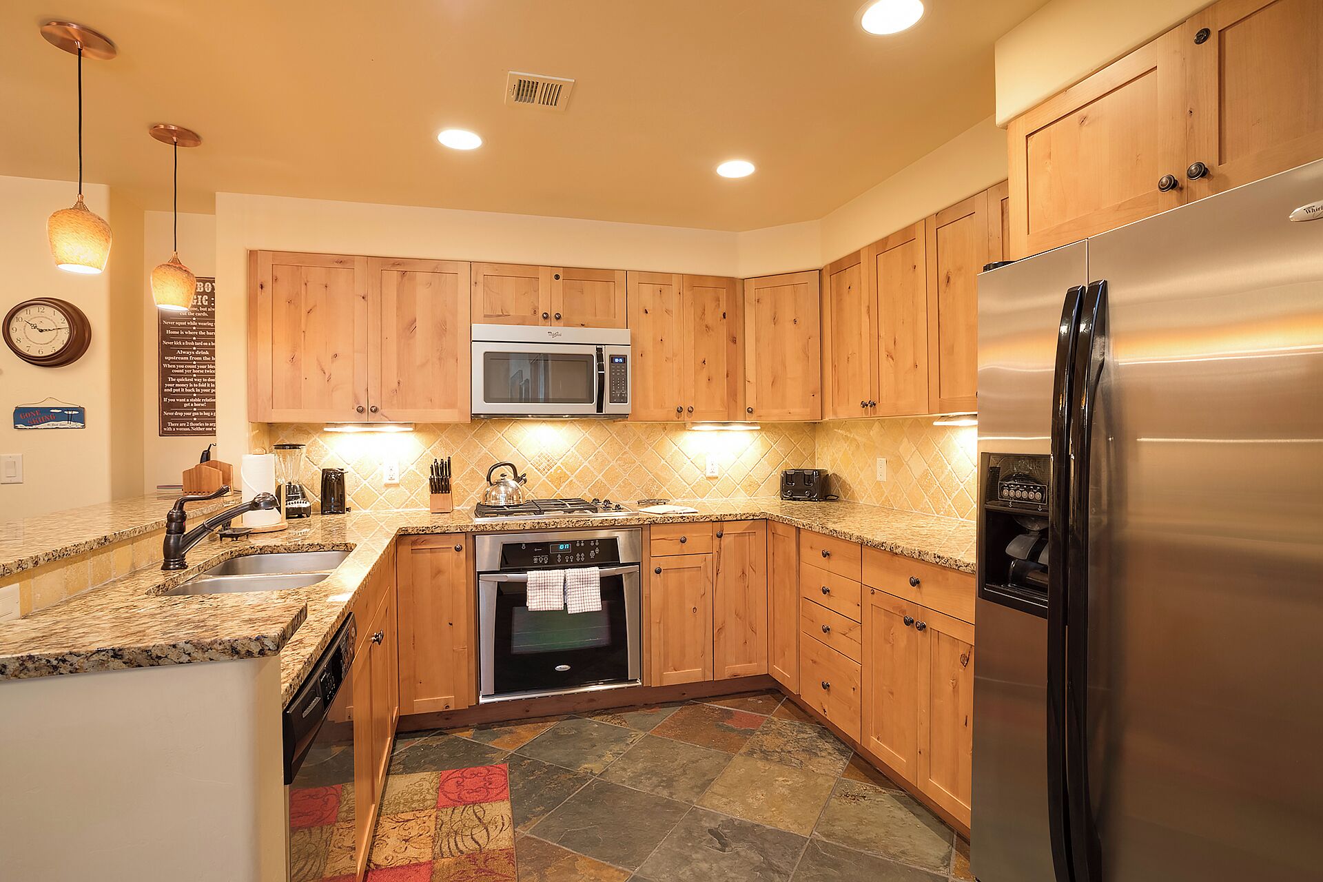A kitchen with wooden cabinets, a stainless steel refrigerator, a microwave, and a dishwasher.