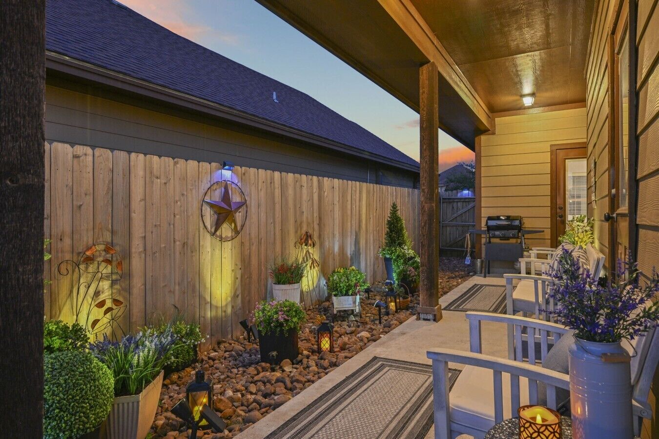 A patio area with a wooden fence, outdoor seating, and potted plants.