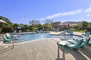 A swimming pool with lounge chairs and a covered seating area.