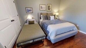 A bedroom with two beds, a nightstand, a lamp, and framed pictures on the wall.