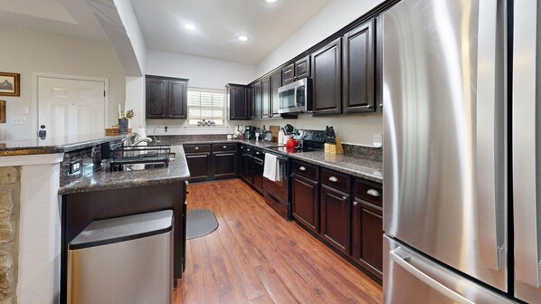 A modern kitchen with dark wood cabinets, stainless steel appliances, and a granite countertop.