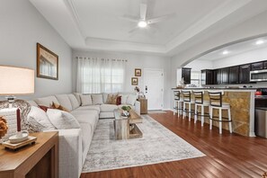 Uma sala de estar moderna com um sofá seccional, uma mesa de centro e um espaço de jantar com banquetas.