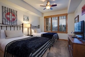 A bedroom with two beds, a ceiling fan, a window with blinds, and a desk with a computer. - BL6102 | Unforgettable Mtn Getaway | 4 Pools | Walk to Mountain | Air Chilling (Steamboat Springs)