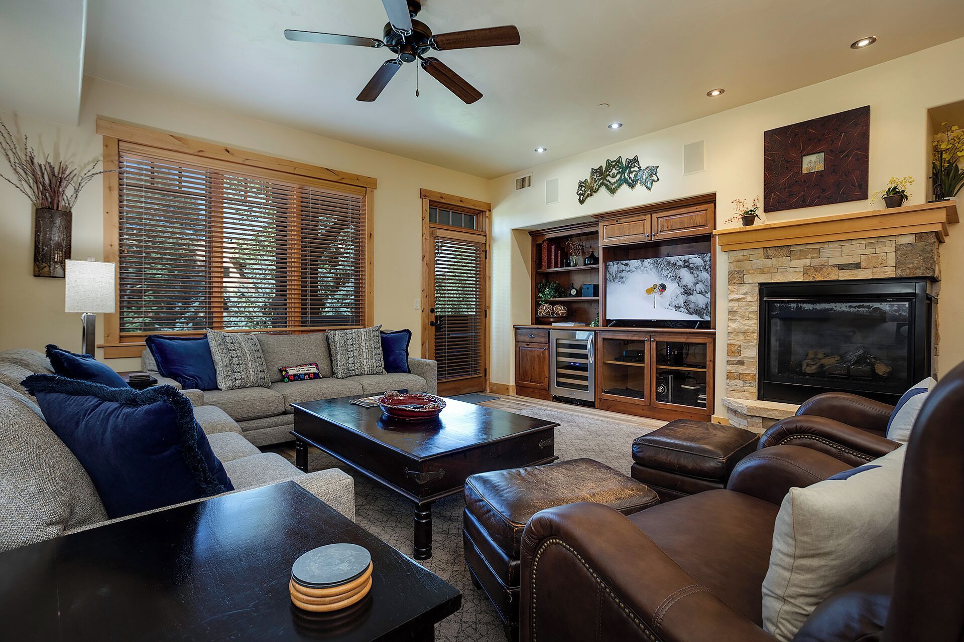 A living room with a fireplace, a ceiling fan, and a television.