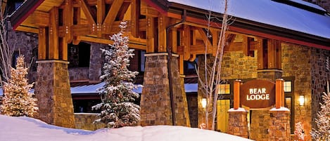 A lodge with a stone facade, wooden beams, and a sign reading "BEAR LODGE."