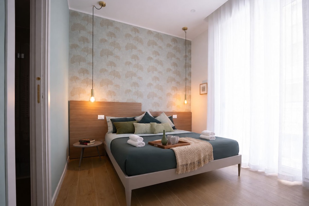 A modern bedroom with a bed, bedside tables, and a window with curtains.