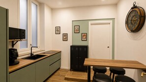 A compact kitchen with a coffee machine, a sink, and a wooden table with a bench. - Arcadia Rooms Palermo (Palermo)