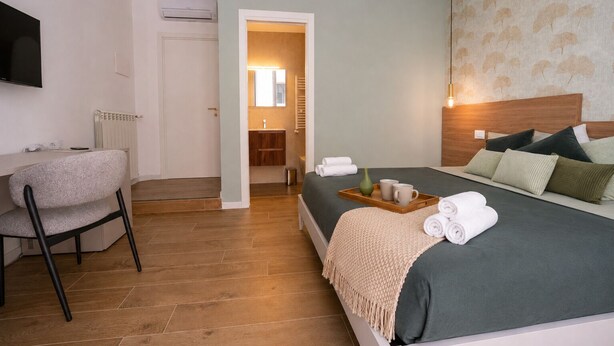 A hotel room with a bed, a desk, a chair, a bathroom, and a TV. - Arcadia Rooms Palermo (Palermo)