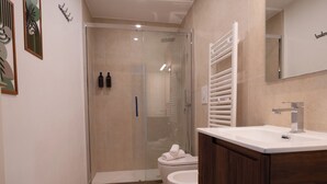 A modern bathroom with a glass-enclosed shower, a white toilet, and a wooden vanity with a mirror. - Arcadia Rooms Palermo (Palermo)