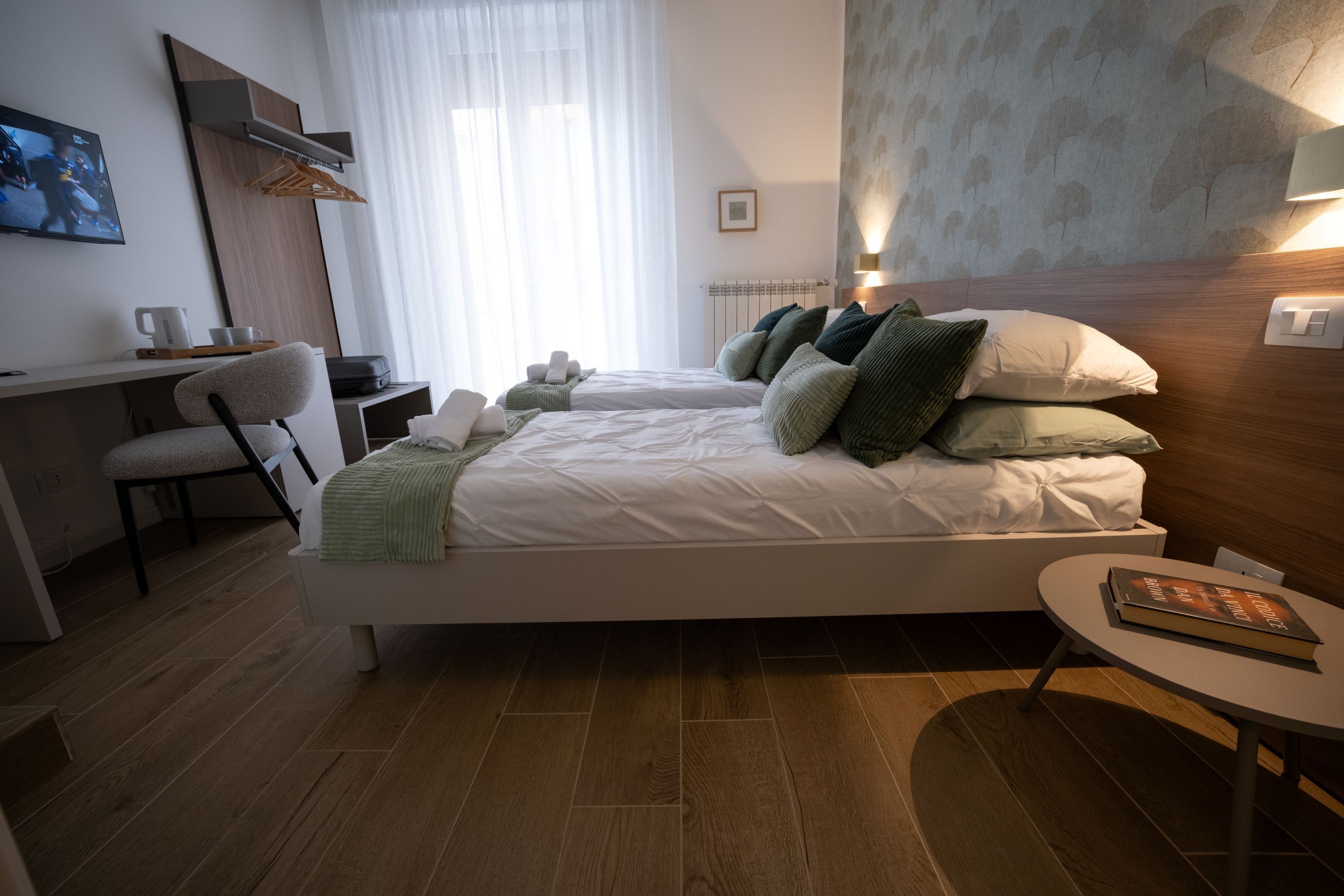 A modern hotel room with a bed, a desk, and a chair.