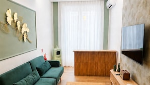 A modern living room with a green sofa, a wooden coffee table, and a flat-screen TV mounted on the wall. - Arcadia Rooms Palermo (Palermo)