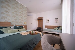 Ett hotellrum med en säng, ett skrivbord, en stol, en garderob och ett litet bord med ett bricka på.
