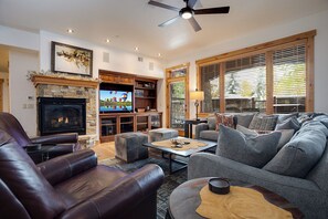 A spacious living room with a fireplace, a television, leather sofas, and a ceiling fan. - BL6108 | Ultimate Vacation Experience | Private Hot Tub | Air Chilling | Pools (Steamboat Springs)