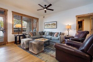 Ein Wohnzimmer mit Ecksofa, Ledersessel, Couchtisch und Deckenventilator.