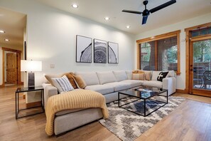 Ein Wohnzimmer mit Sofa, Couchtisch und Lampe. An der Wand hängen drei gerahmte Kunstwerke.