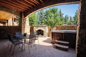 An outdoor patio with stone walls, a brick floor, and a stone fireplace. - BL6110 | Beautifully Appointed Mtn Condo | Private Hot Tub | Air Chilling | Pool (Steamboat Springs)