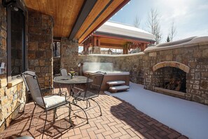 An outdoor patio with stone walls, a hot tub, and a fireplace. - BL6111 | Private Courtyard with Hot Tub | Air Chilling | Pools | Wood Flooring (Steamboat Springs)