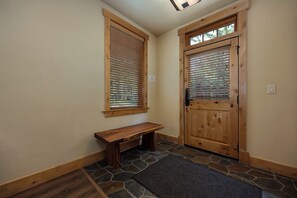 A wooden bench, a stone-tiled floor, and a wooden door with blinds. - BL6112 | Cozy Mtn Condo | Private Courtyard and Hot Tub | Air Chilling (Steamboat Springs)