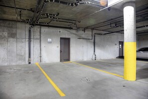 A parking garage with concrete walls, a yellow and white pillar, and a door marked with the number 6115. - BL6115 | Unique and Beautiful Getaway | Heated Garage| Hot Tubs | Air Chilling (Steamboat Springs)