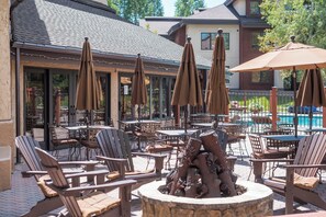 An outdoor patio area with multiple tables and chairs, umbrellas, and a decorative fire pit. - BL6115 | Unique and Beautiful Getaway | Heated Garage| Hot Tubs | Air Chilling (Steamboat Springs)