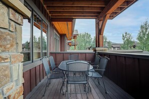 A covered outdoor patio with a wooden deck, stone wall, and metal chairs and table. - BL6201 | Perfect for the Family | 4 Pools | Air Chilling | Close to Slopes (Steamboat Springs)