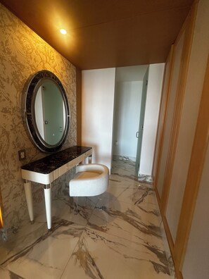 A bathroom with a marble floor, a round mirror, a white vanity, and a towel rack.