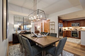 Een moderne keuken met roestvrijstalen apparatuur, houten keukenkastjes en een eethoek met een houten tafel en gestoffeerde stoelen.