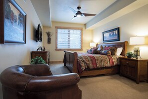 A bedroom with a bed, a chair, a nightstand, a ceiling fan, and a window with blinds. - BL6209 | Mountain Views | 4 Pools | 10 Hot Tubs | Air Chilling | Close to Mtn (Steamboat Springs)