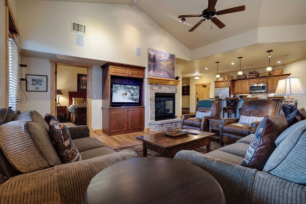 A spacious living room with a fireplace, leather sofas, a flat-screen TV, and a ceiling fan. - BL6302 | Top Floor with Stellar Views | Short Walk to Mtn | Air Chilling (Steamboat Springs)