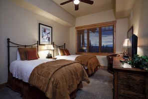 A bedroom with two beds, a ceiling fan, a window with blinds, a desk with a lamp, and a framed picture on the wall. - BL6302 | Top Floor with Stellar Views | Short Walk to Mtn | Air Chilling (Steamboat Springs)