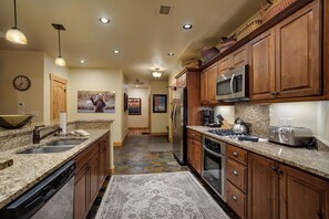 A spacious kitchen with granite countertops, wooden cabinets, a stainless steel refrigerator, and a microwave. - BL6302 | Top Floor with Stellar Views | Short Walk to Mtn | Air Chilling (Steamboat Springs)