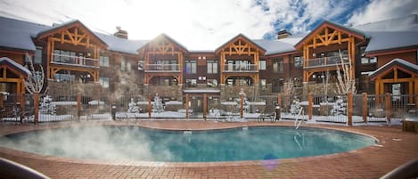 A poolside area with a hot tub, lounge chairs, and a building with multiple balconies.