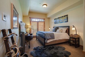 A bedroom with a bed, a desk, a chair, a lamp, and a window with blinds. - BL6307 | Vaulted Ceilings | Amazing Views | Air Chilling | 10 Hot Tubs (Steamboat Springs)