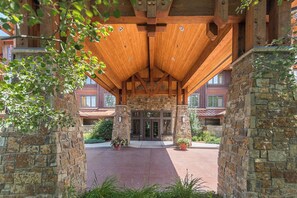A building entrance with a stone facade, wooden beams, and potted plants. - BL6307 | Vaulted Ceilings | Amazing Views | Air Chilling | 10 Hot Tubs (Steamboat Springs)