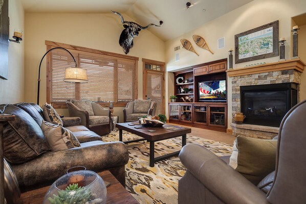 A living room with a fireplace, a television, and a bull head mounted on the wall. - BL6307 | Vaulted Ceilings | Amazing Views | Air Chilling | 10 Hot Tubs (Steamboat Springs)