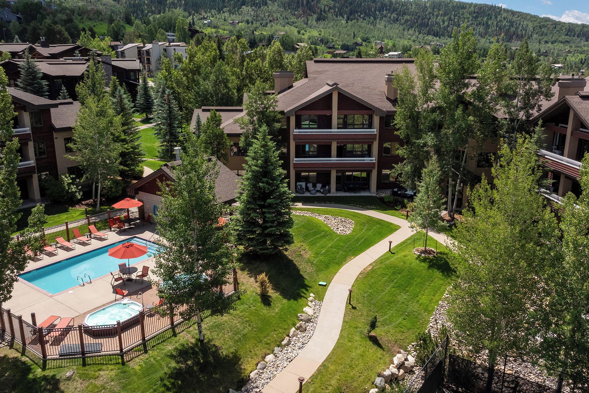 A resort with a swimming pool, lounge chairs, and a well-maintained lawn.